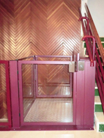 Plataforma salvaescaleras vertical modelo izaro de color rojo instalada en una comunidad de vecinos de Xtiva (Valencia).