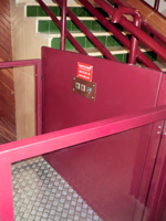 Plataforma salvaescaleras vertical modelo izaro de color rojo instalada en una comunidad de vecinos de Xtiva (Valencia).